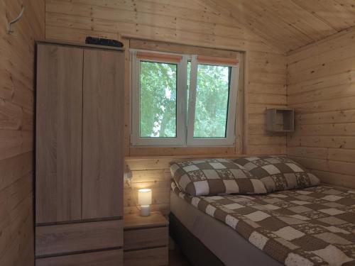 Habitación pequeña con cama y ventana en Domek mazurski ze świerka syberyjskiego., en Zdory