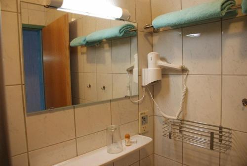 uma casa de banho com um espelho e um lavatório com um secador de cabelo em Zöchbauer Gästehaus - Hotel Garni em Kapelln