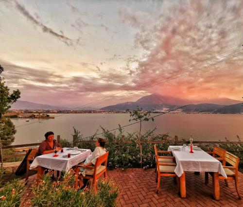 two people sitting at a table with a view of a lake at Ece Hotel Sovalye Island in Fethiye