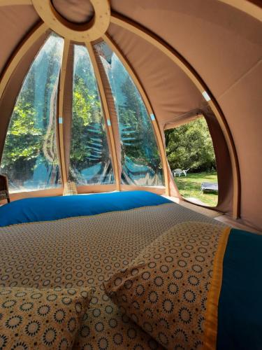 米奧的住宿－La Wigwam Bleu du Domaine du Pas de l'âne，帐篷内的一张床位,设有两个窗户