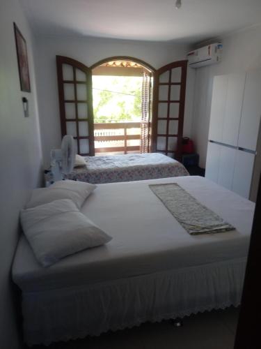 a bedroom with two beds and a window at Cantinho do Canaã in Arraial do Cabo