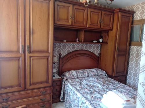 1 dormitorio con 1 cama y armarios de madera en CASA DO RIZAL en Lagoa