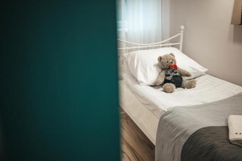 a stuffed teddy bear sitting on a bed at Eromeni Apartments in Biały Dunajec