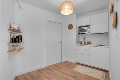 une cuisine avec des armoires blanches et un plancher en bois dans l'établissement Le Bayamo - 7min à pied de la station Jeanne d'Arc, à Toulouse