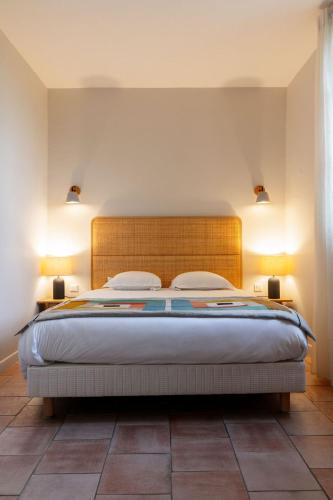 a bedroom with a large bed with two lamps at Hôtel l'Arena in Fréjus