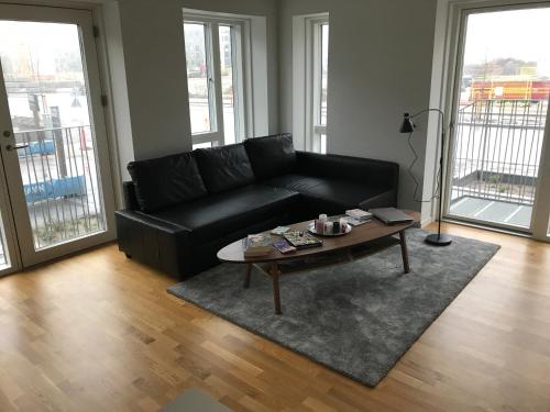 a living room with a black couch and a coffee table at Big Room In SHARED APARTMENT With King Size Bed in Copenhagen