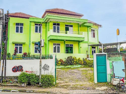 a yellow and green house with a blue door at SPOT ON 91325 Pondok Hijau Guest House Syariah in Cilimus 2