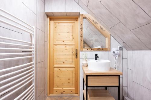 a bathroom with a sink and a wooden door at Pokoje Gościnne Maryniarczyk in Kościelisko