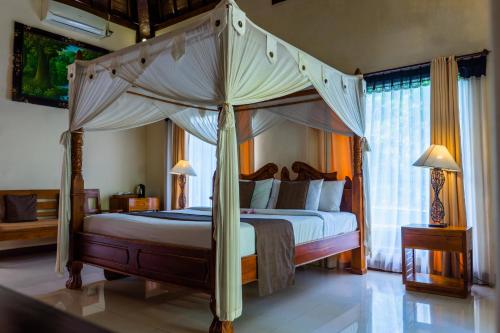 a bedroom with a canopy bed in a room at Villa JJ and Spa Ubud in Ubud