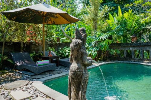 a statue of a bear with an umbrella next to a pool at Villa JJ and Spa Ubud in Ubud