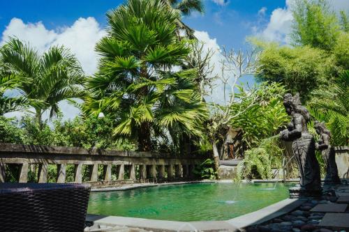 a fountain in the middle of a garden with palm trees at Villa JJ and Spa Ubud in Ubud