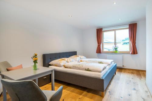 een slaapkamer met een bed, een tafel en een raam bij Landhaus Rosner in Dorfgastein