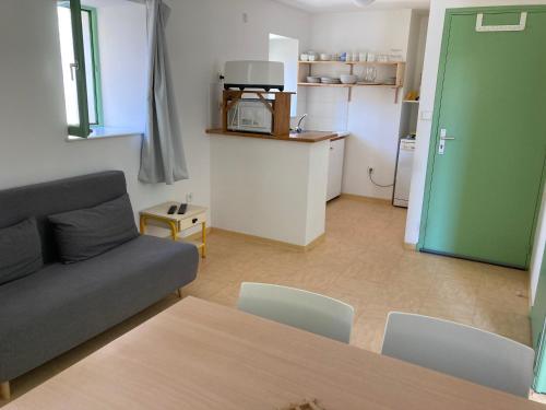sala de estar con sofá, mesa y cocina en Gîte Communal des Remparts, en Le Val