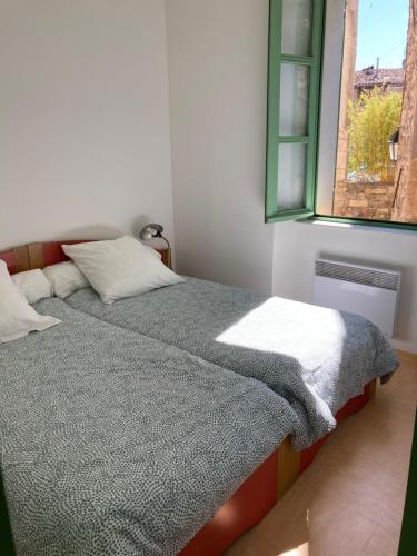 une chambre avec un lit et une fenêtre dans l'établissement Gîte Communal des Remparts, à Le Val