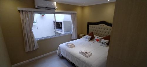 a bedroom with a bed with white sheets and a window at Casa en San Pedro en Boulevard, equipada. in San Pedro