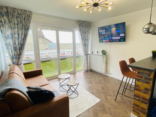 a living room with a couch and a large window at L'instant présent - Petite vue mer in Villers-sur-Mer