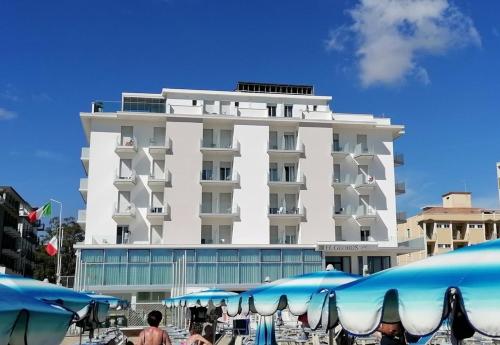 a large white building with umbrellas in front of it at Hotel Globus in Bellaria-Igea Marina