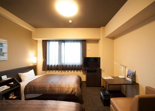 een hotelkamer met een bed, een bureau en een raam bij Hotel Route Inn Ono in Ono