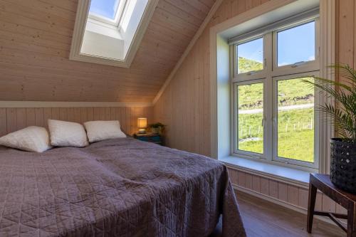 a bedroom with a bed and two windows at Feriehus med flott havutsikt ved Hauklandstranden in Leknes