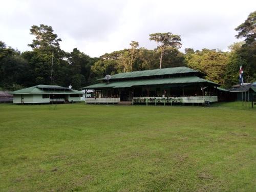 Barrigones的住宿－Corcovado Guide House，一座在田野上拥有绿色屋顶的建筑