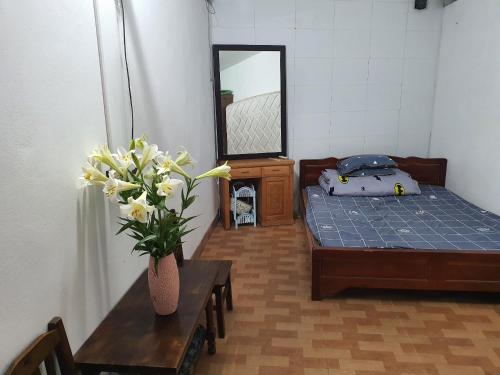 ein Schlafzimmer mit einem Bett und einem Tisch mit einer Blumenvase in der Unterkunft Nha Xanh Ha Long Homestay in Hạ Long