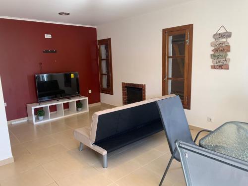 a living room with a flat screen tv and a couch at Aroeira Beach House in Aroeira