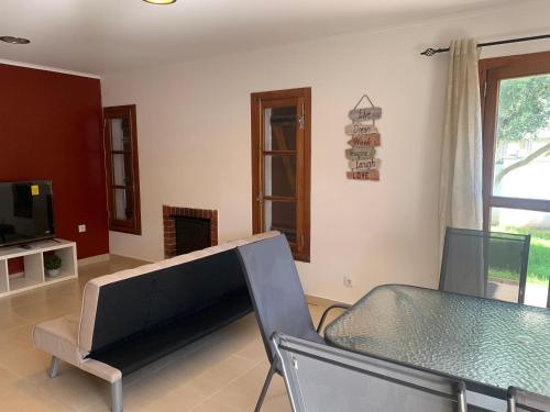 a living room with a glass table and a television at Aroeira Beach House in Aroeira