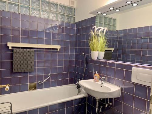 ザンクト・ペーター・オルディングにあるFerienwohnung "Zaunkönig"の青いタイル張りのバスルーム(シンク、バスタブ付)