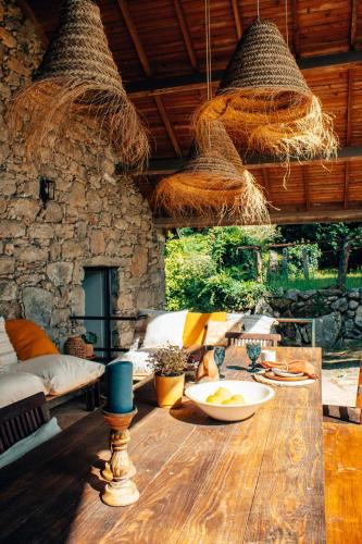 a room with a wooden table with baskets hanging from the ceiling at Just Like Home - Quinta da Cavada em Vilar de Mouros in Caminha