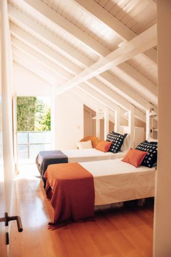 two beds in a room with a wooden ceiling at Just Like Home - Quinta da Cavada em Vilar de Mouros in Caminha