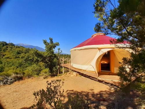 duży żółty namiot z czerwonym dachem na polu w obiekcie Yourte contemporaine avec magnifique vue sur les montagnes w mieście Rigarda
