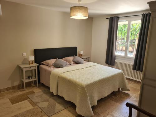 een slaapkamer met een bed met een witte deken en een raam bij les olivades in Cavaillon