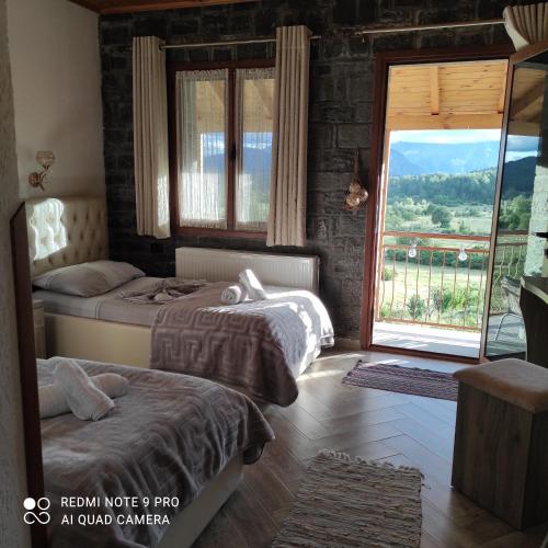 a bedroom with two beds and a large window at Bujtina Vila Dodo in Leskovik