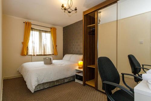 a bedroom with a bed and a window and chairs at 4 beds Sleeps 5- Elegance Leisure Stay, Oldham in Lees