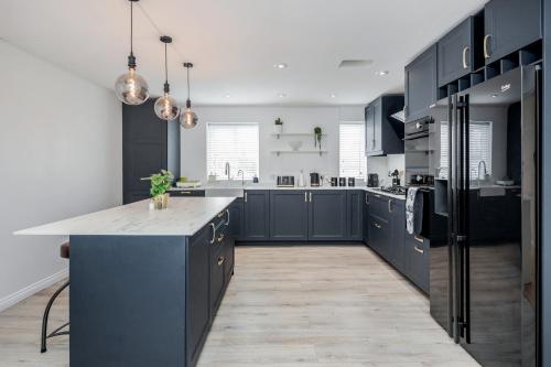 a large kitchen with blue cabinets and a large island at Large Penthouse by Damask Homes with Parking in Redbridge