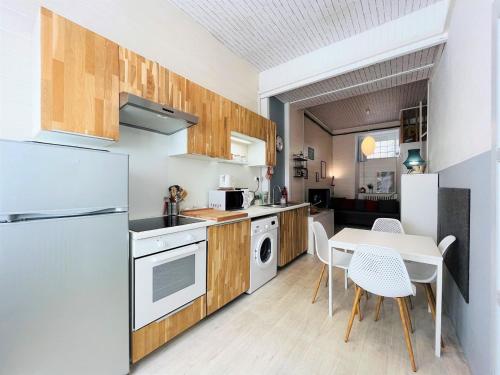 une cuisine avec un réfrigérateur blanc et une table dans l'établissement Charmant T2 avec WIFI au cœur du Mont-Dore, proche Thermes, idéal pour 5 pers. et petit chien - FR-1-608-221, à Le Mont-Dore