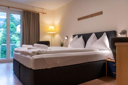 a hotel room with a large bed with white pillows at Grischalodge das Hotel mit Bergblick seit 1929 - schlicht, preiswert und mit einem touch Nostalgie in Parpan