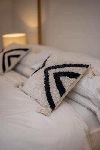 a black and white pillow on a white bed at Spacious & Stylish StoneHous Cottage in Forfar