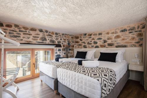 a bedroom with a large bed and a stone wall at Palio Damnoni House in Damnoni