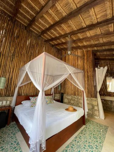 a bedroom with a bed with a mosquito net at Piña Coloradas Ecolodge in Yuluc