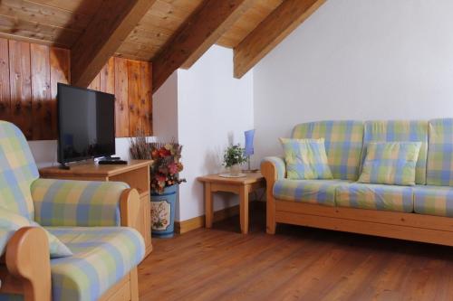 a living room with two couches and a flat screen tv at LA PULCE INNEVATA - Agenzia Dolomiti Affitti in Passo Rolle