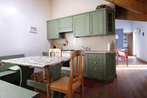 a kitchen with green cabinets and a table with chairs at LA PULCE INNEVATA - Dolomiti Affitti in Passo Rolle