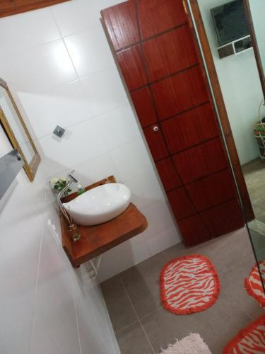 a bathroom with a white sink and a red door at Pousada Chalé na Roça Penedo in Penedo