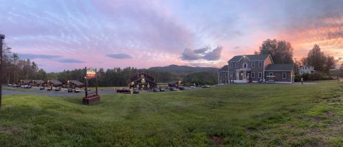 a large house on a green field with a sunset at Swiss Chalets Village Inn in North Conway