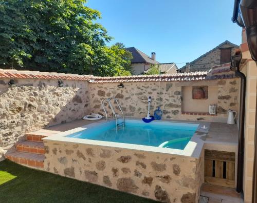 uma piscina com uma parede de pedra em Casa Rural Las Cigüeñas de Las Navillas em Navas de Ríofrío