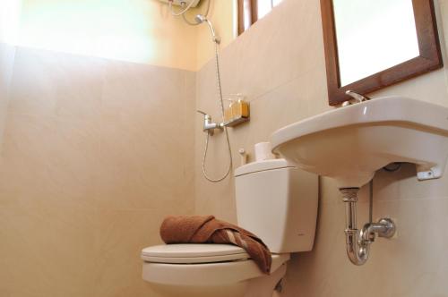 a bathroom with a sink and a toilet and a mirror at Bemo Corner Guest House in Kuta