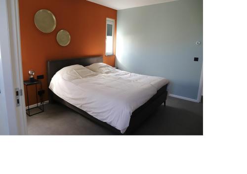 1 cama en un dormitorio con pared de color naranja en Chaletparc Krabbenkreek Zeeland - Chalet 232, en Sint Annaland