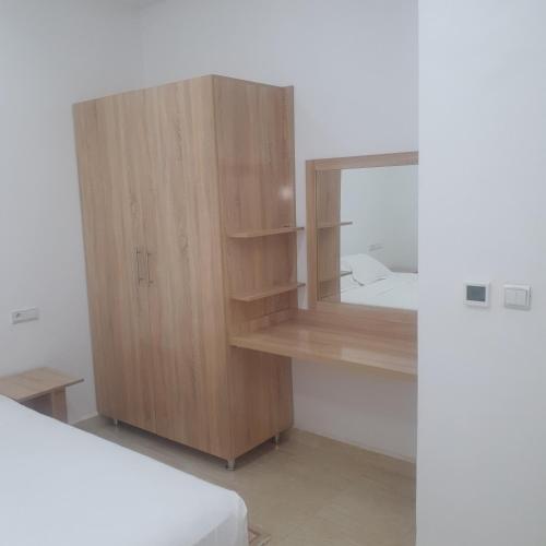 a bedroom with a wooden cabinet with a mirror at RESIDENCE OUARZAZATE in Ouarzazate