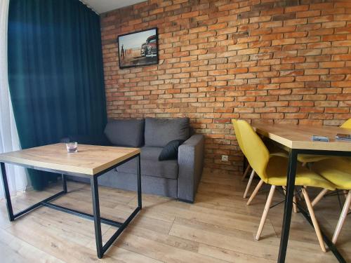 ein Wohnzimmer mit einem Sofa, Tischen und einer Ziegelwand in der Unterkunft Apartament 24 in Mysłowice