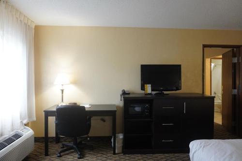 a hotel room with a desk with a computer and a television at Baymont by Wyndham Bridgeport/Frankenmuth in Bridgeport